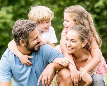 une famille avec 2 enfants dans l'herbe, complicité, communication relationnelle
