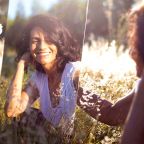 une jene femme dans la nature qui se regarde dans un miroir en souriant, elle prend la vie de bon coté